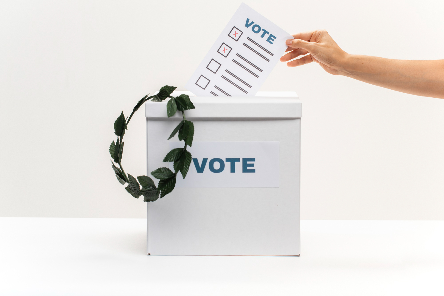 tangan seseorang sedang memasukkan kertas suara pemilihan ke dalam kotak suara